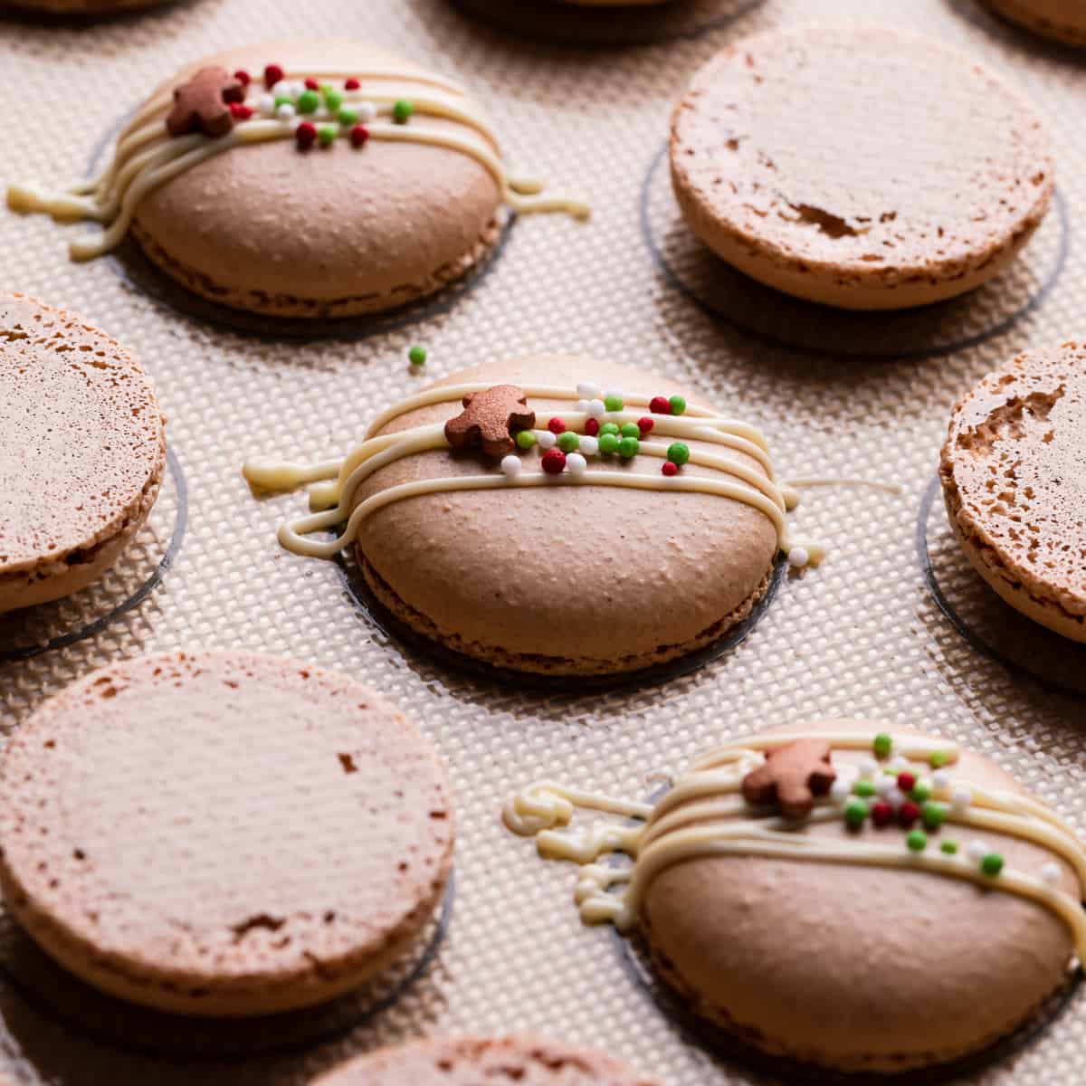 ginger macaron shells drizzled with white chocolate and festive sprinkles.