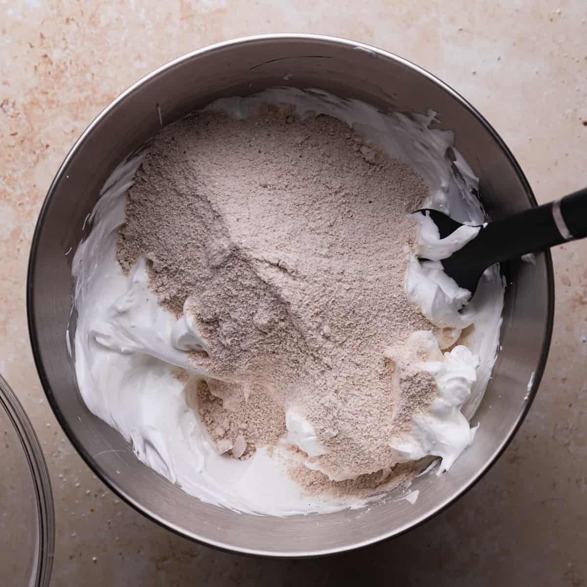 dry ingredients on top of the meringue in a metal mixing bowl with spatula.