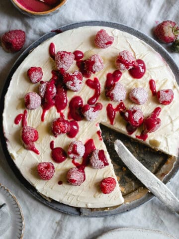 raspberry and white chocolate cheesecake with slice cut out of it.