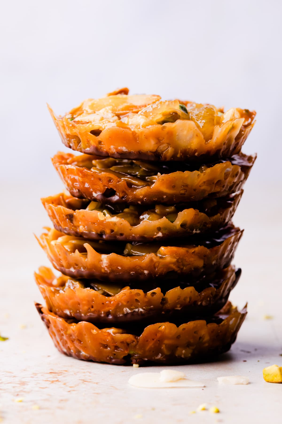 stack of six small almond and pistachio florentines dipped in dark chocolate.