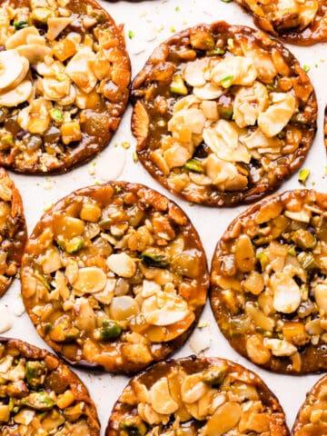 almond florentines shaped into large round discs with some chopped nuts around them.