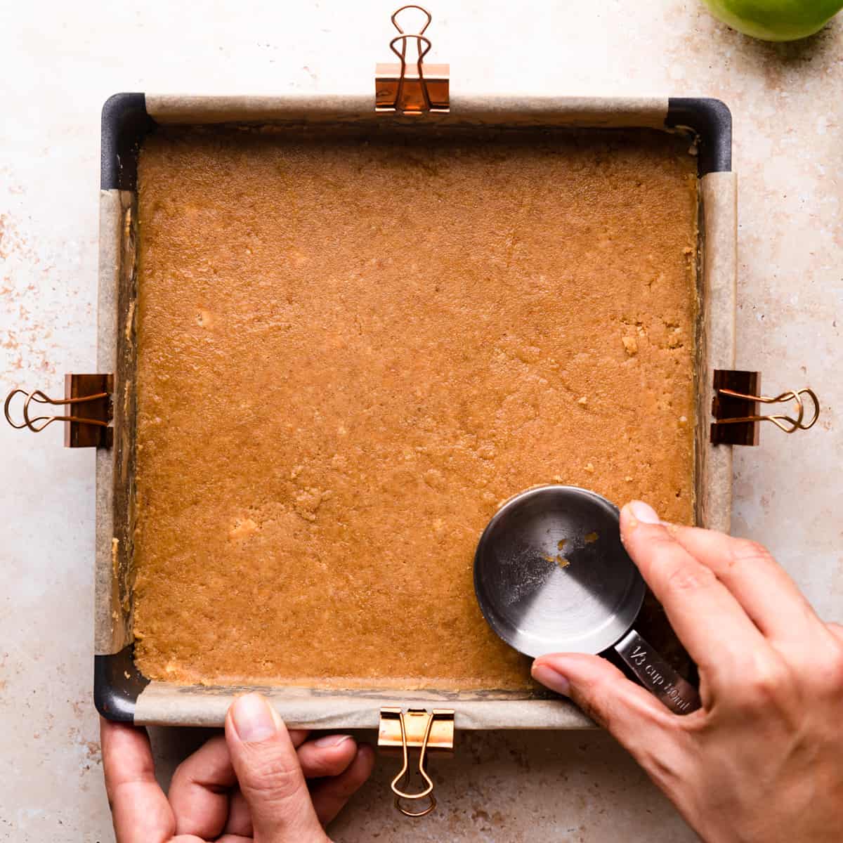 cheesecake crust being pressed into baking tin.