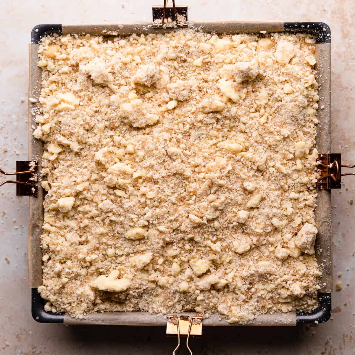 square baking pan with apple cheesecake topped with crumble.