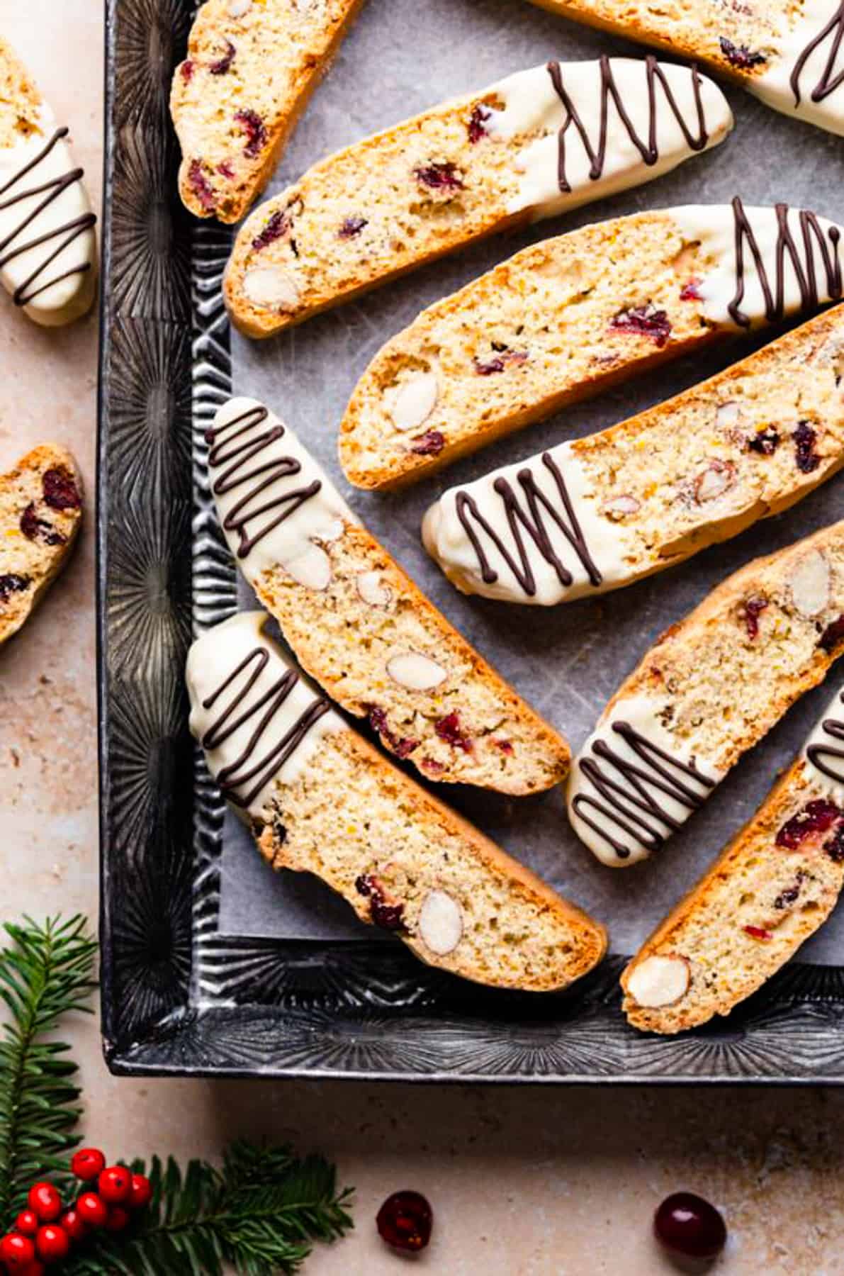 cranberry almond biscotti dipped in white chocolate and drizzled with more chocolate inside of the baking tin.
