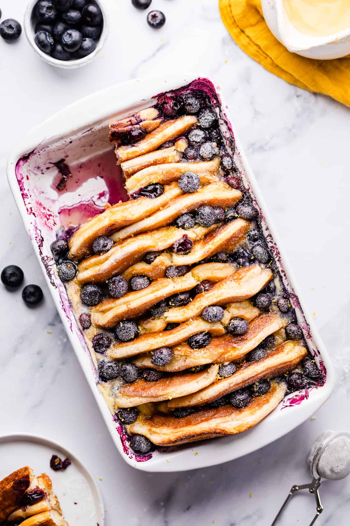 blueberry pancake casserole dusted with icing sugar and with a portion cut out.