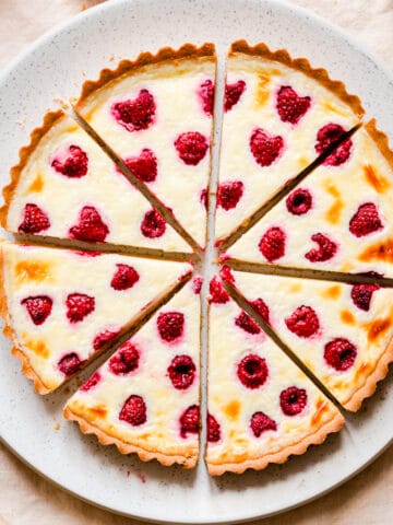 raspberry mascarpone tart cut into 8 slices on a large plate.